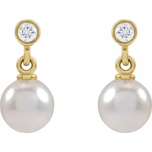 Close-up of 14K gold pearl stud earrings featuring diamonds