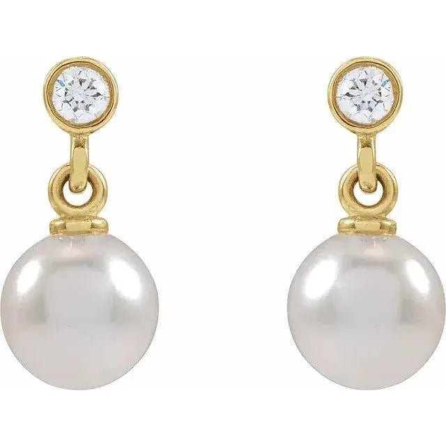 Close-up of 14K gold pearl stud earrings featuring diamonds