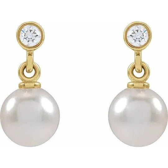 Close-up of 14K gold pearl stud earrings featuring diamonds