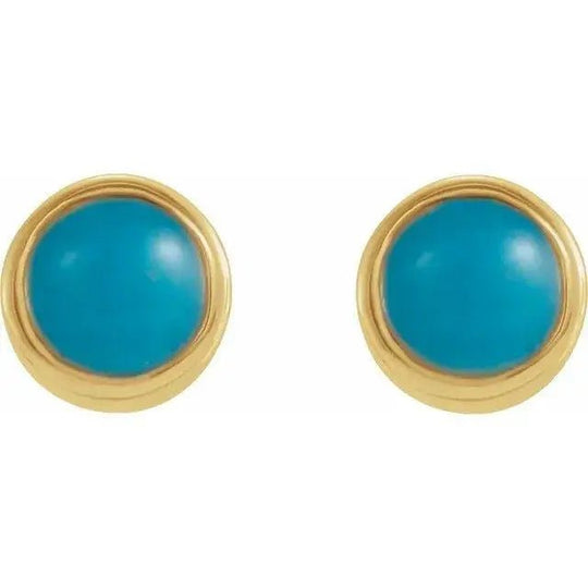 Close-up of handcrafted gold earrings featuring bezel-set turquoise stones