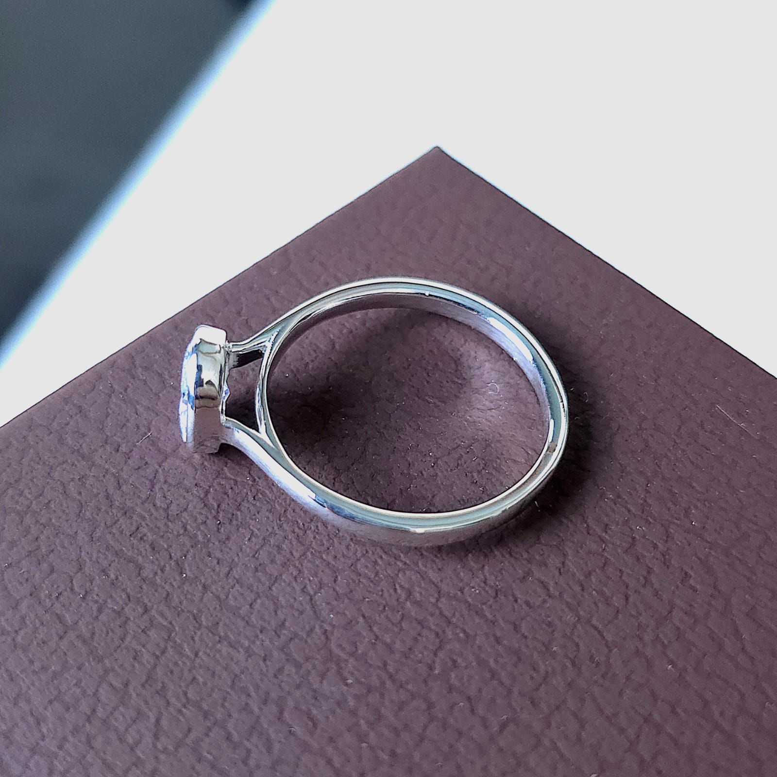 Inside profile of the ring resting on brown surface, showing the under-bezel architecture.