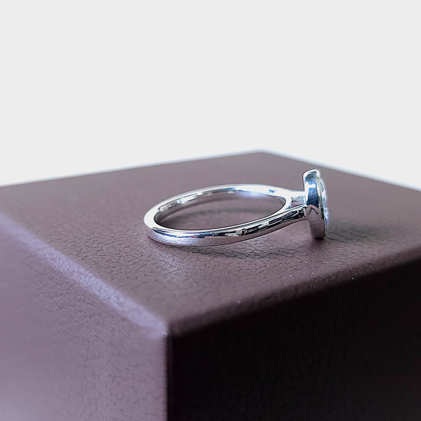 Left-side portrait of oval bezel engagement ring emphasizing band thickness and stone height.