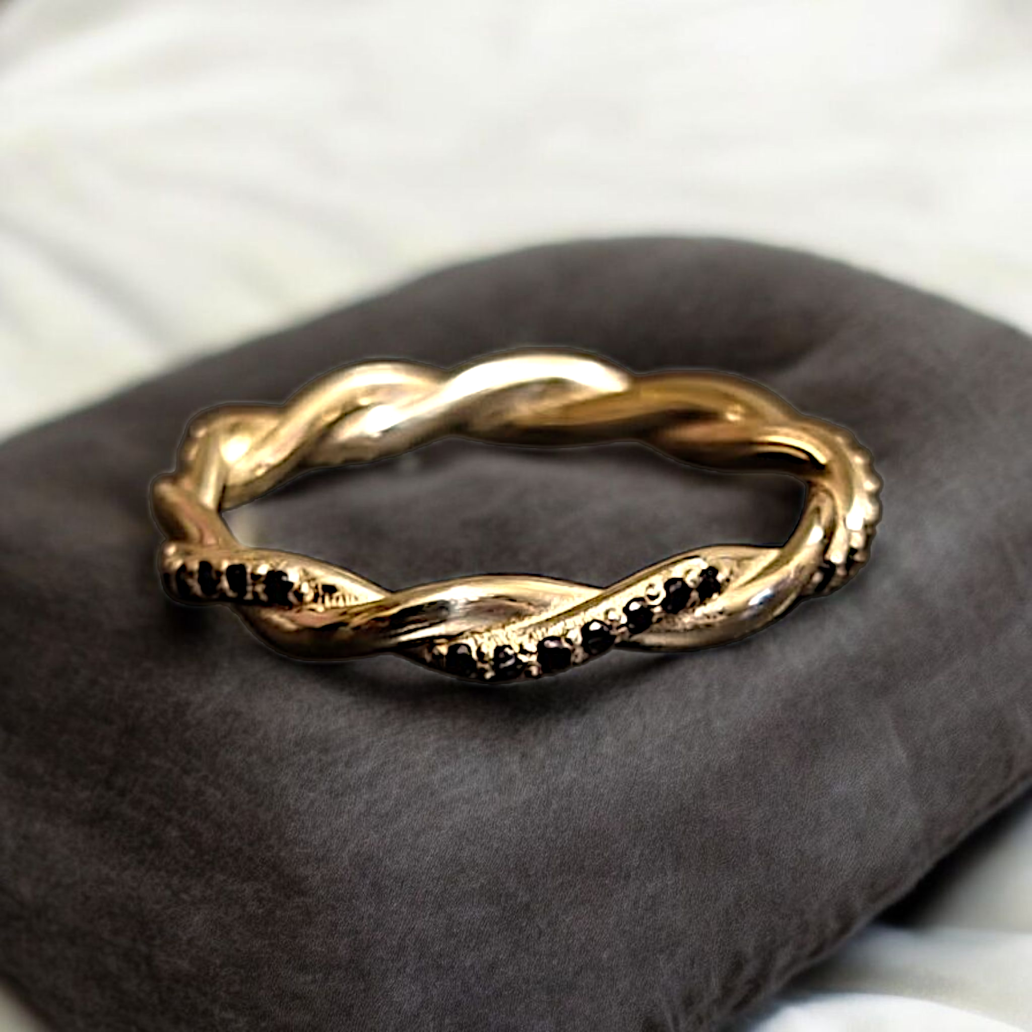 Black diamond twisted ring resting on velvet cushion, handcrafted in NYC