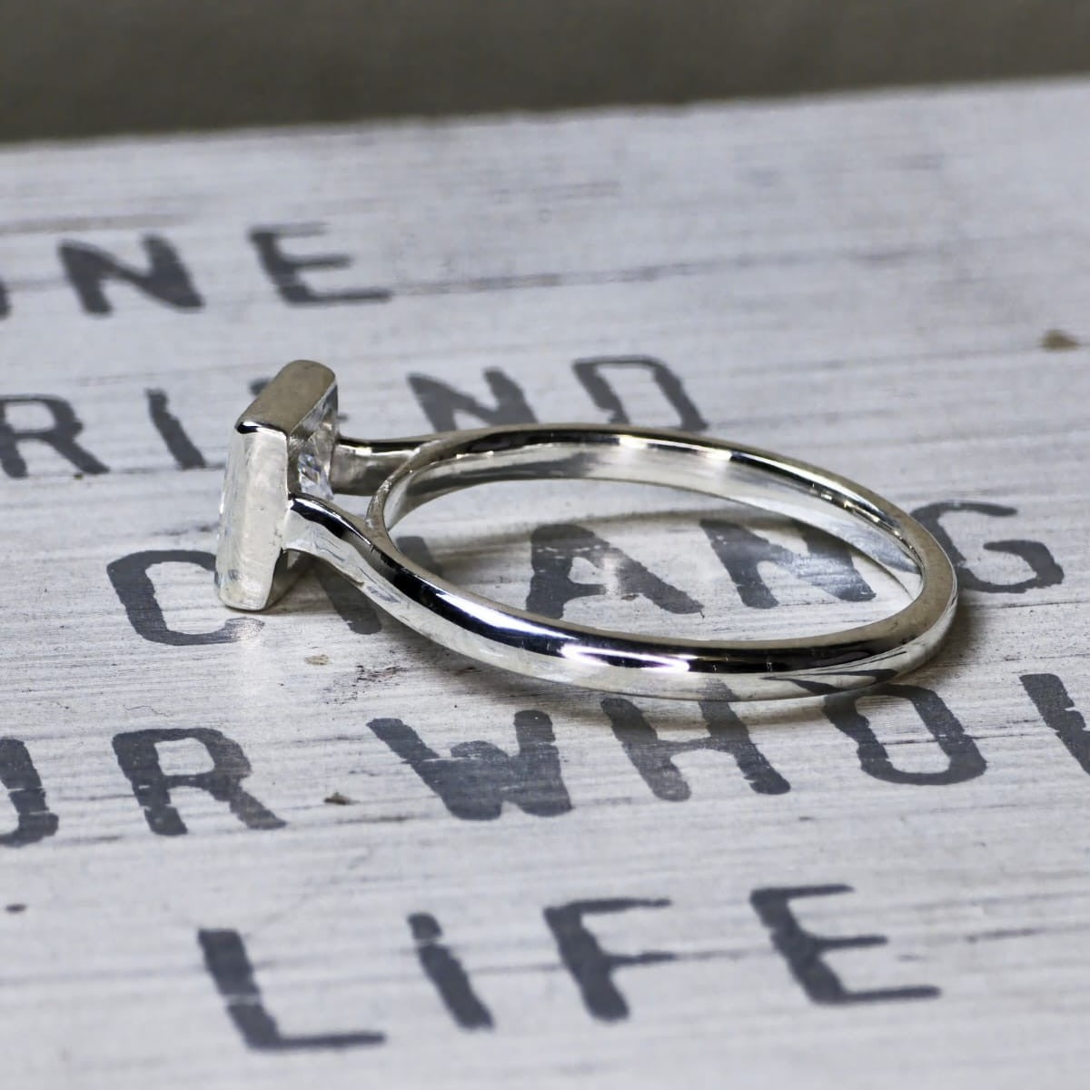 Side view of 14K white gold bezel set square diamond engagement ring with 2mm band