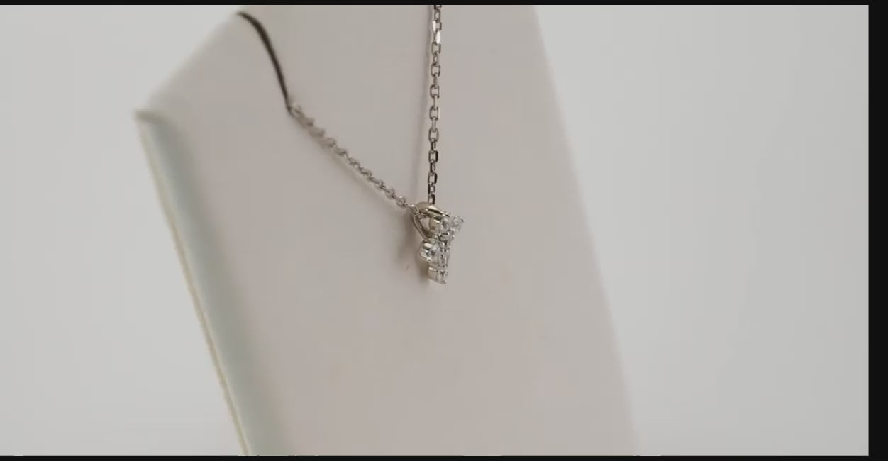 Side profile of the white gold mini diamond cross necklace displayed on a jewelry stand, highlighting its delicate craftsmanship and adjustable chain.