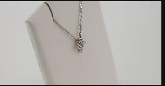 Side profile of the white gold mini diamond cross necklace displayed on a jewelry stand, highlighting its delicate craftsmanship and adjustable chain.